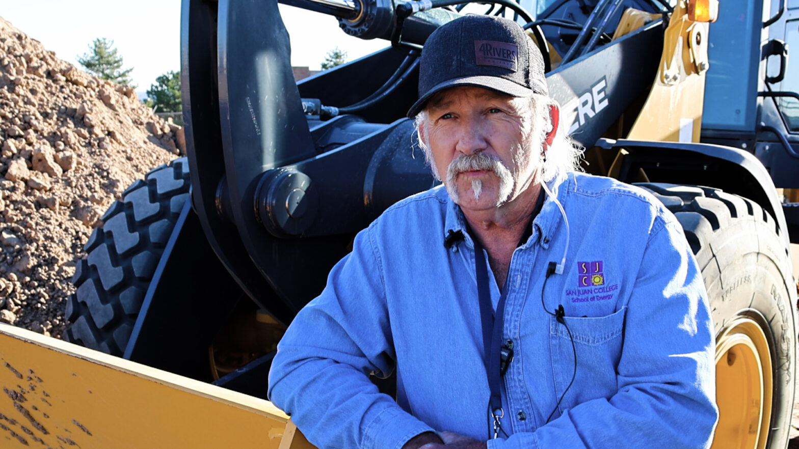 Patrick Smith, San Juan College instructor, beside a John Deere dozer.